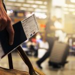 Persona con passaporto e carta d'imbarco in aeroporto.